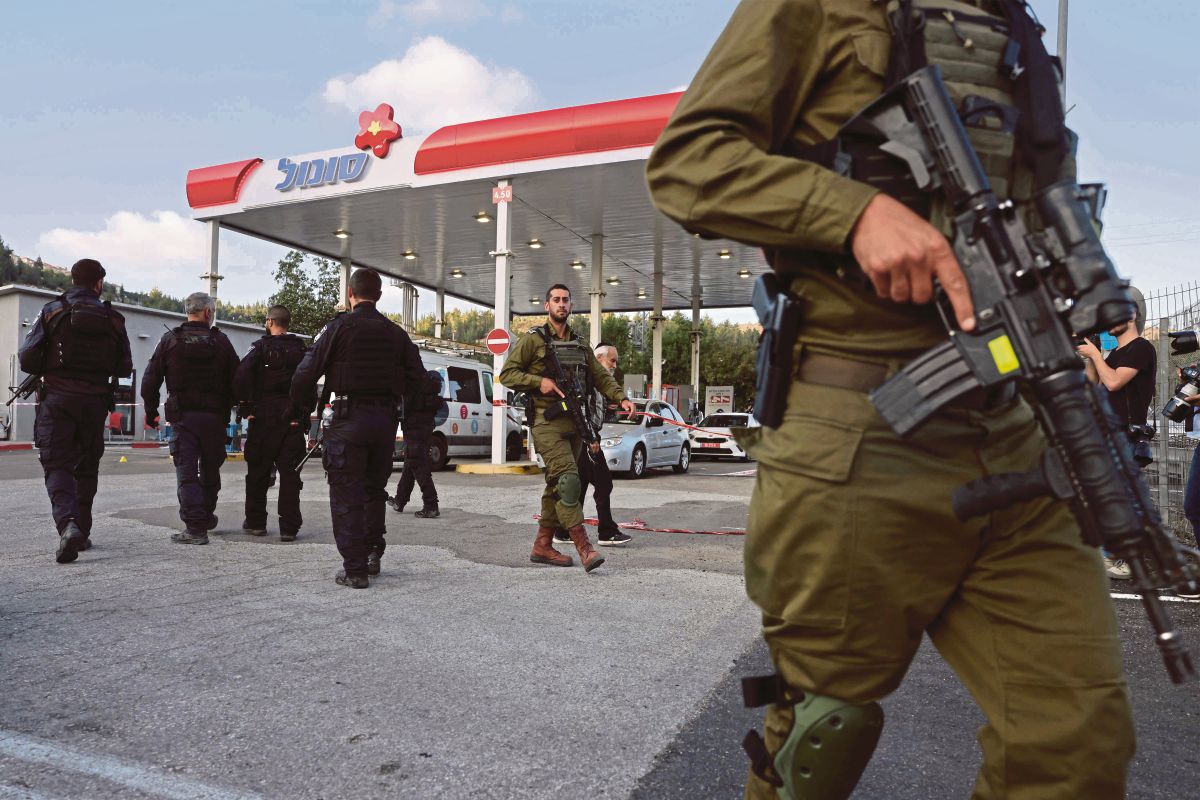 POLIS dan tentera Israel berkawal di stesen minyak di Eli, salah satu penempatan haram Yahudi di Tebing Barat, susulan kejadian empat orang ditembak mati. FOTO AFP