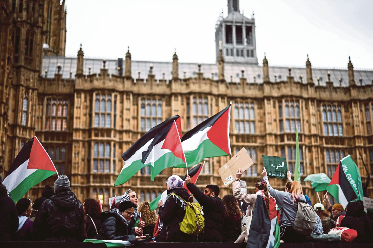 PENUNJUK perasaan mengibarkan bendera Palestin ketika protes di Dataran Parlimen, London. FOTO AFP 