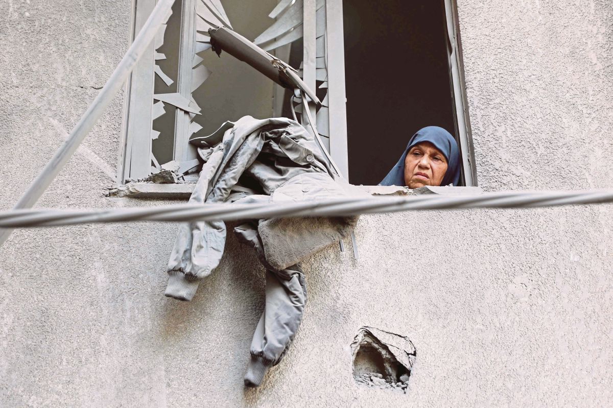 WANITA melihat ke luar tingkap bangunan yang rosak susulan pengeboman Israel di kejiranan Al-Daraj, Gaza. FOTO AFP