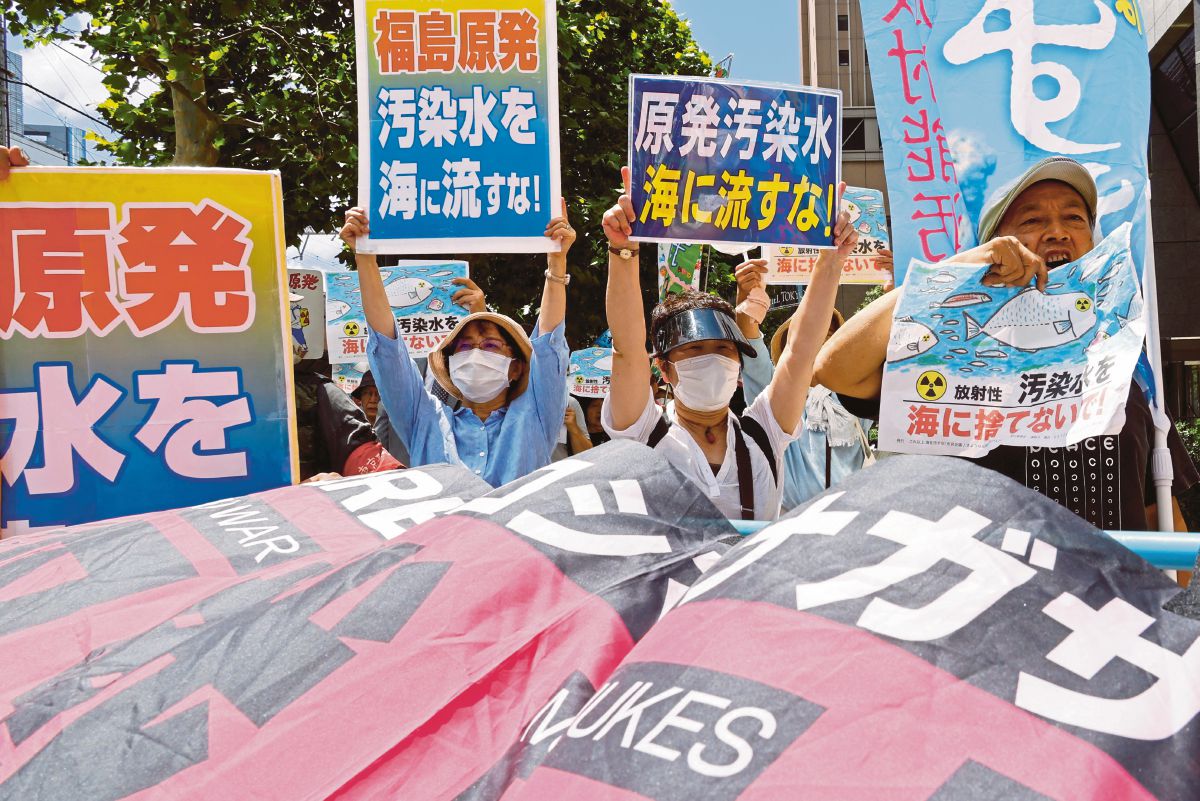 PENUNJUK perasaan memegang poster dan sepanduk bagi menyatakan bantahan terhadap tindakan pelepasan sisa air dari loji nuklear Fukushima. FOTO Reuters