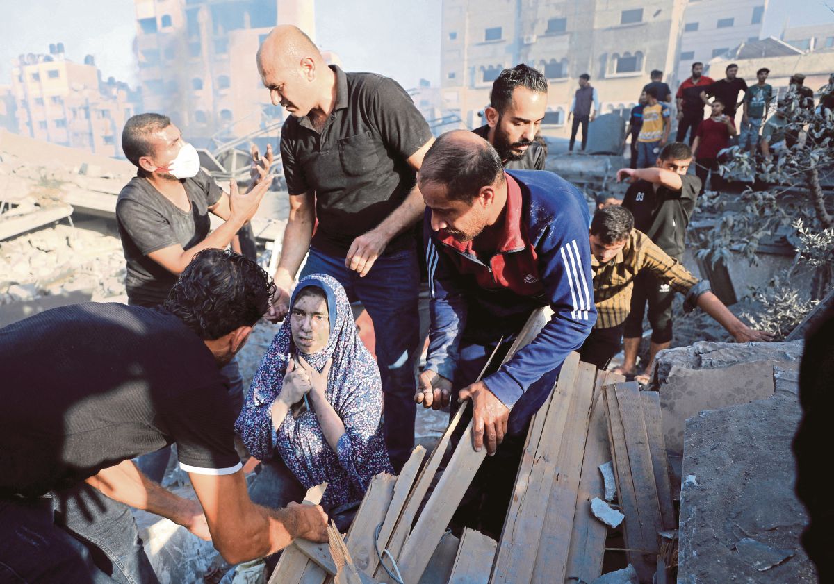 WANITA Palestin menerima bantuan, ketika orang ramai mencari mangsa yang terkorban susulan serangan udara di Gaza. FOTO Reuters 