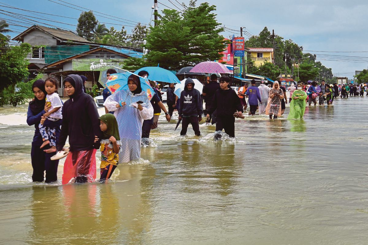 ORANG ramai meredah banjir susulan hujan lebat di wilayah selatan Narathiwat, Thailand. FOTO AFP