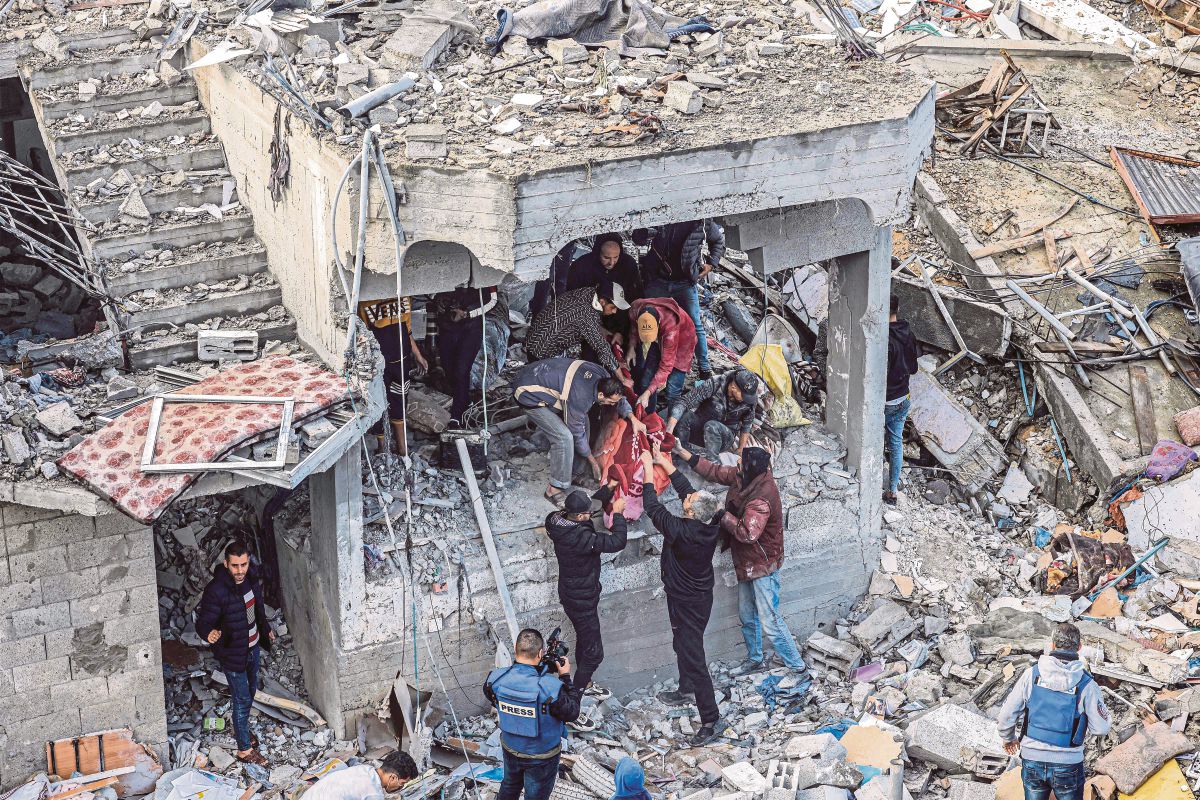 LELAKI mengeluarkan mayat mangsa dari runtuhan bangunan di kem pelarian al-Maghazi, susulan serangan Israel. FOTO AFP