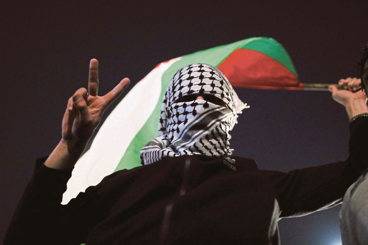 PENUNJUK perasaan memegang bendera Palestin ketika demonstrasi di Amman, bagi menyatakan sokongan kepada penduduk Gaza. FOTO Reuters