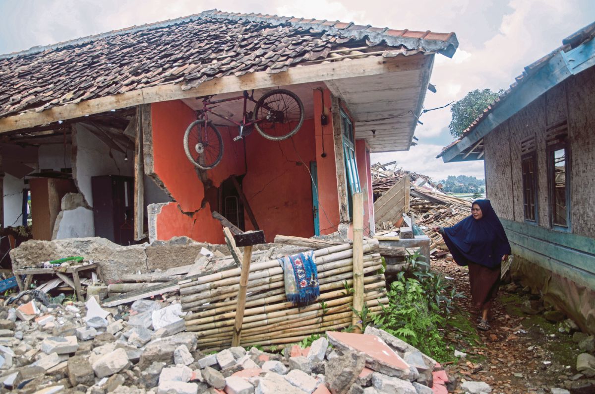 WANITA melihat kerosakan pada rumahnya di Sukamulya, Cianjur. FOTO Reuters