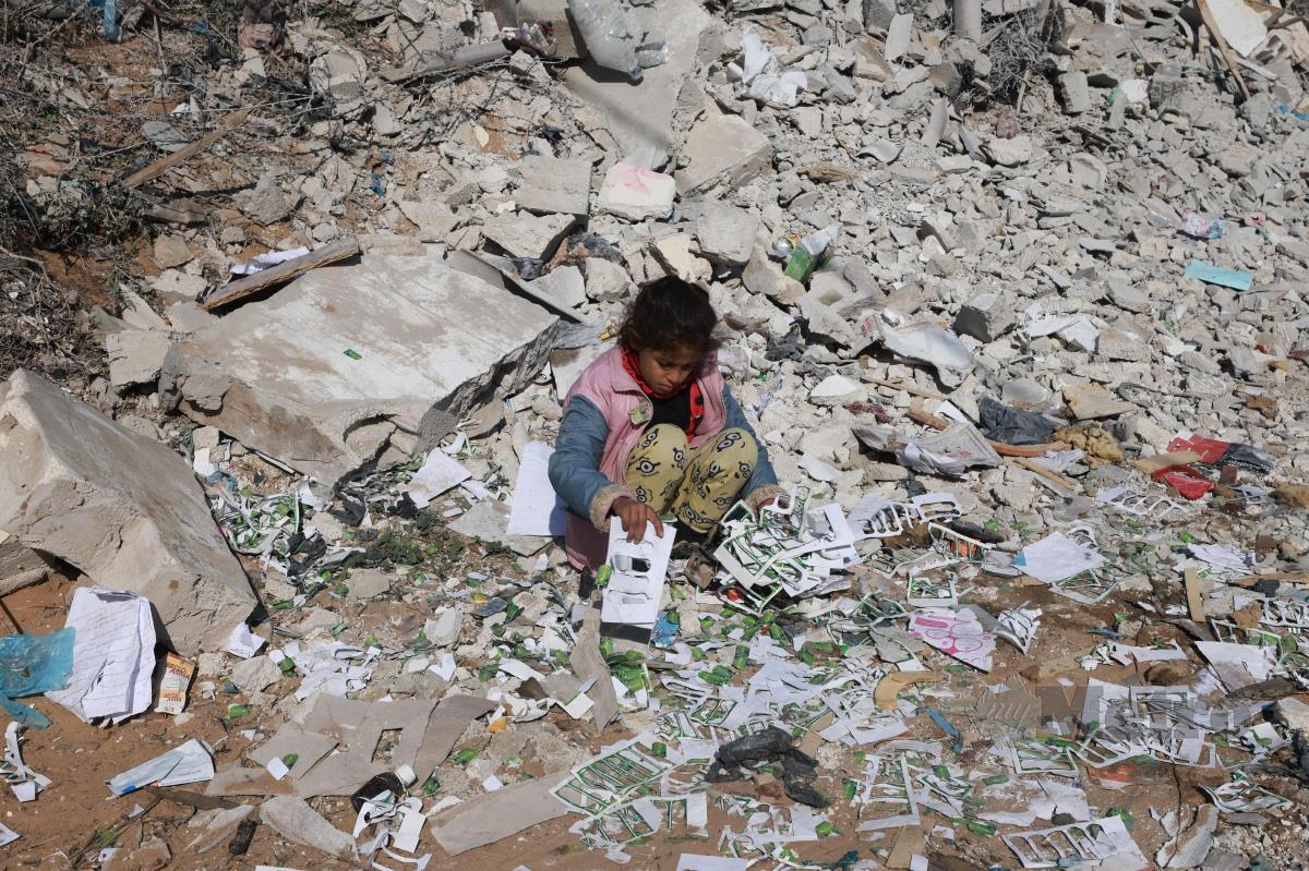 KANAK-KANAK perempuan Palestin mencari barangan di runtuhan bangunan di Khan Yunis, selatan Gaza. FOTO AFP