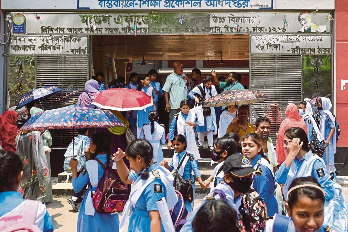 PELAJAR sekolah di Bangladesh menggunakan payung ketika hadir ke sekolah pada Ahad lalu. FOTO AFP