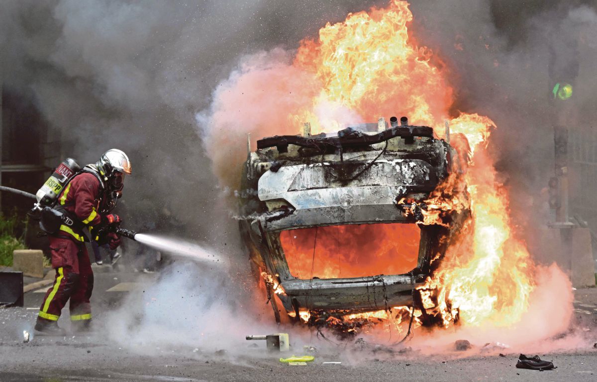 BOMBA memadam kebakaran sebuah kereta ketika protes keganasan susulan kes remaja mati ditembak polis. FOTO AFP