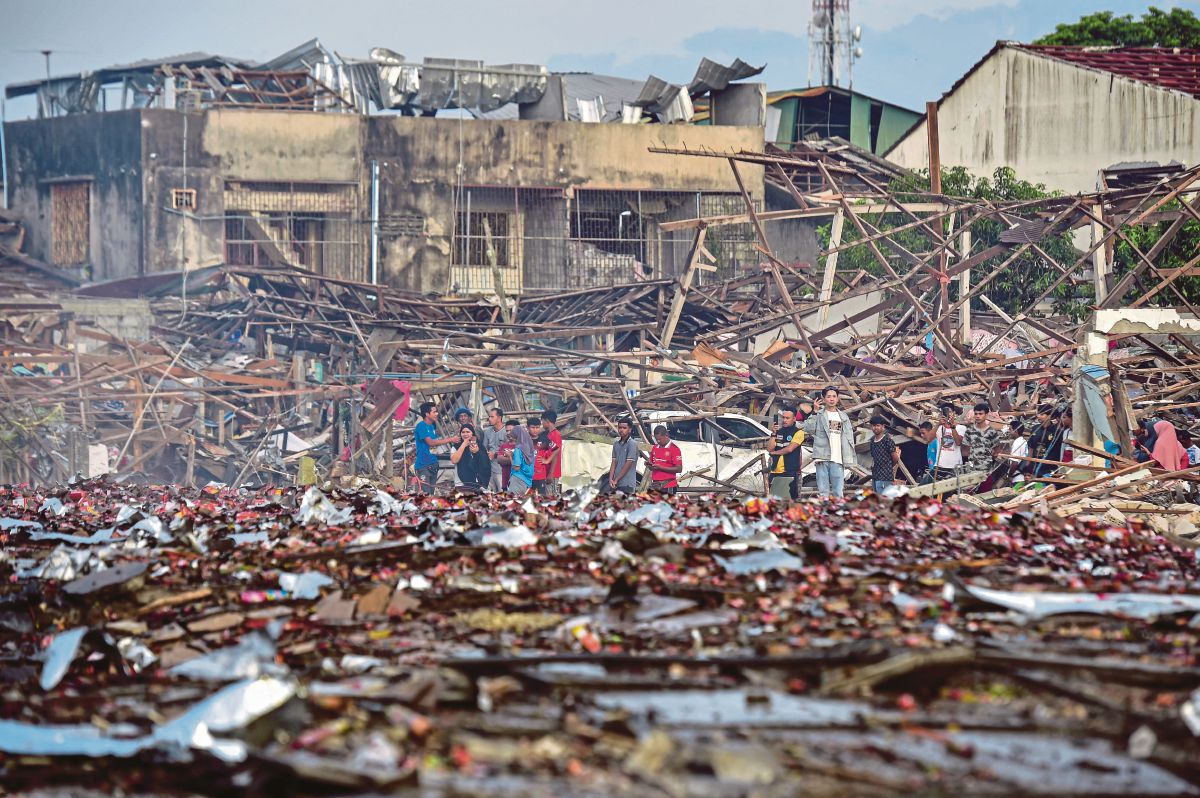 ORANG ramai melihat rumah penduduk yang rosak susulan letupan berkenaan. FOTO AFP