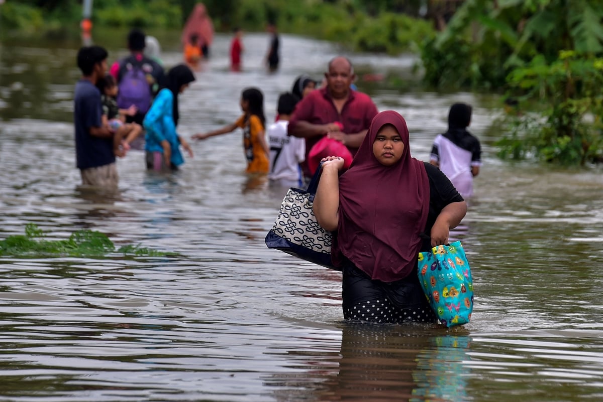 FOTO fail menunjukkan penduduk membawa barangan keperluan ketika banjir di Narathiwat, selatan Thailand. FOTO AFP