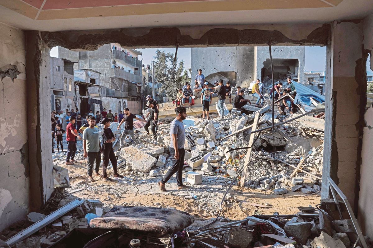 FOTO semalam menunjukkan orang ramai berada berhampiran bangunan yang runtuh susulan serangan Israel di Gaza. FOTO AFP 