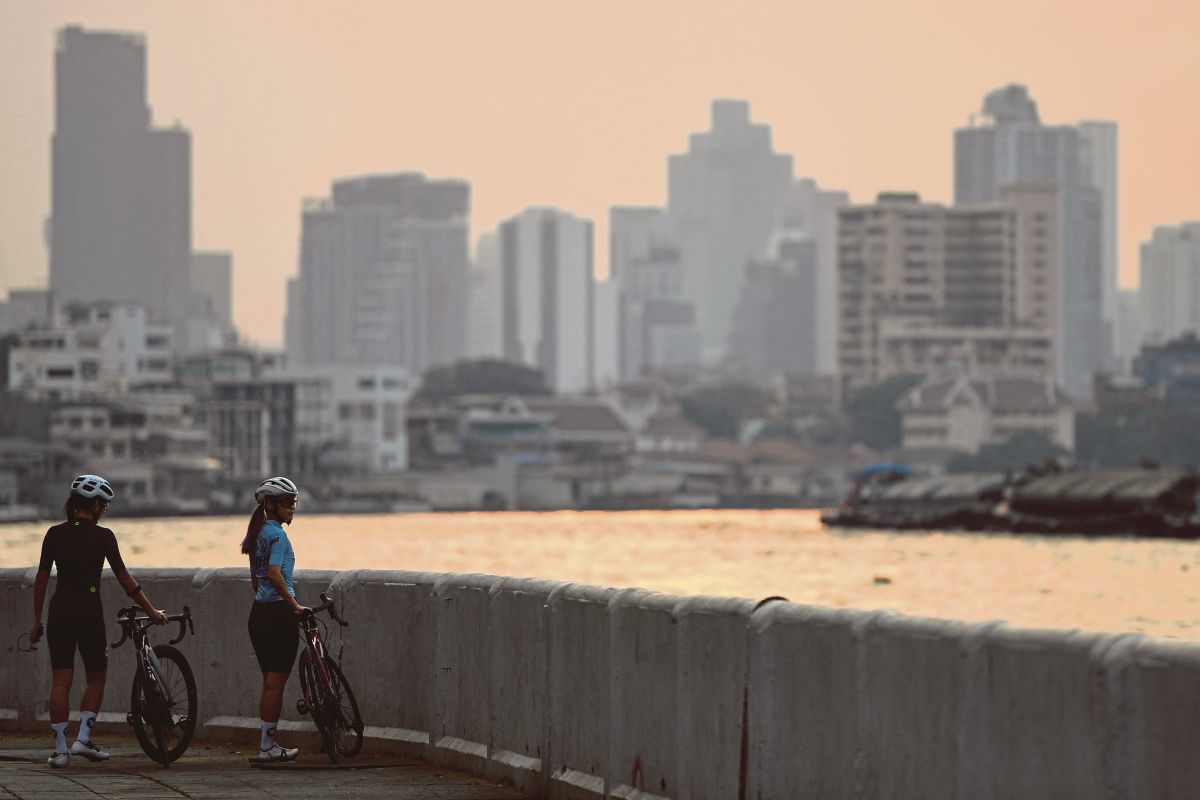 WANITA bersama basikalnya di tebing Sungai Chao Phraya, ketika cuaca berjerebu di Bangkok. FOTO Reuters 