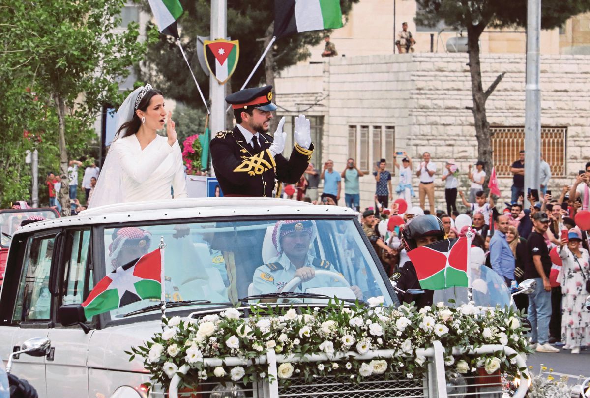 PUTERA Hussein (kanan) dan isterinya, Rajwa al-Seif melambai kepada orang ramai ketika menaiki konvoi kenderaaan selepas majlis pernikahan di Istana Zahran, Amman. FOTO Reuters 