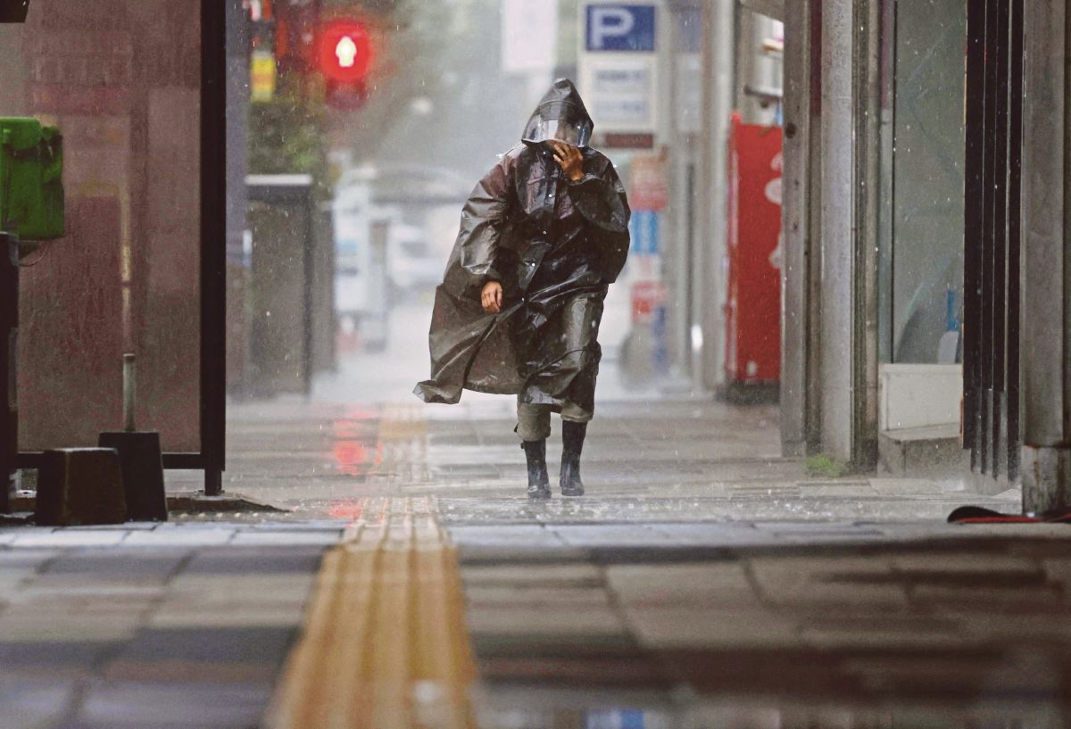 INDIVIDU berjalan ketika hujan lebat dan angin disebabkan oleh Taufan Khanun, di Kagoshima, Jepun. FOTO Kyodo/ Reuters 