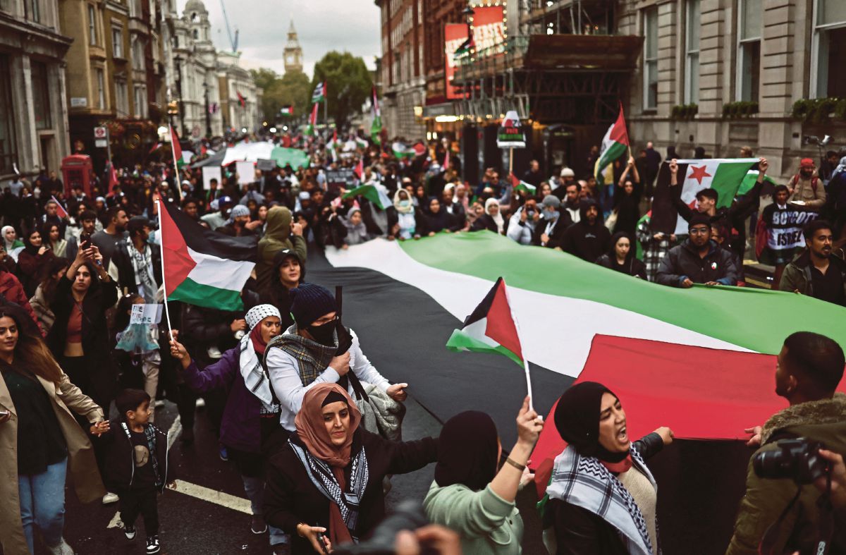 ORANG ramai turut membawa bendera Palestin ketika menyertai perhimpunan solidariti bersama Palestin, di London. FOTO AFP 