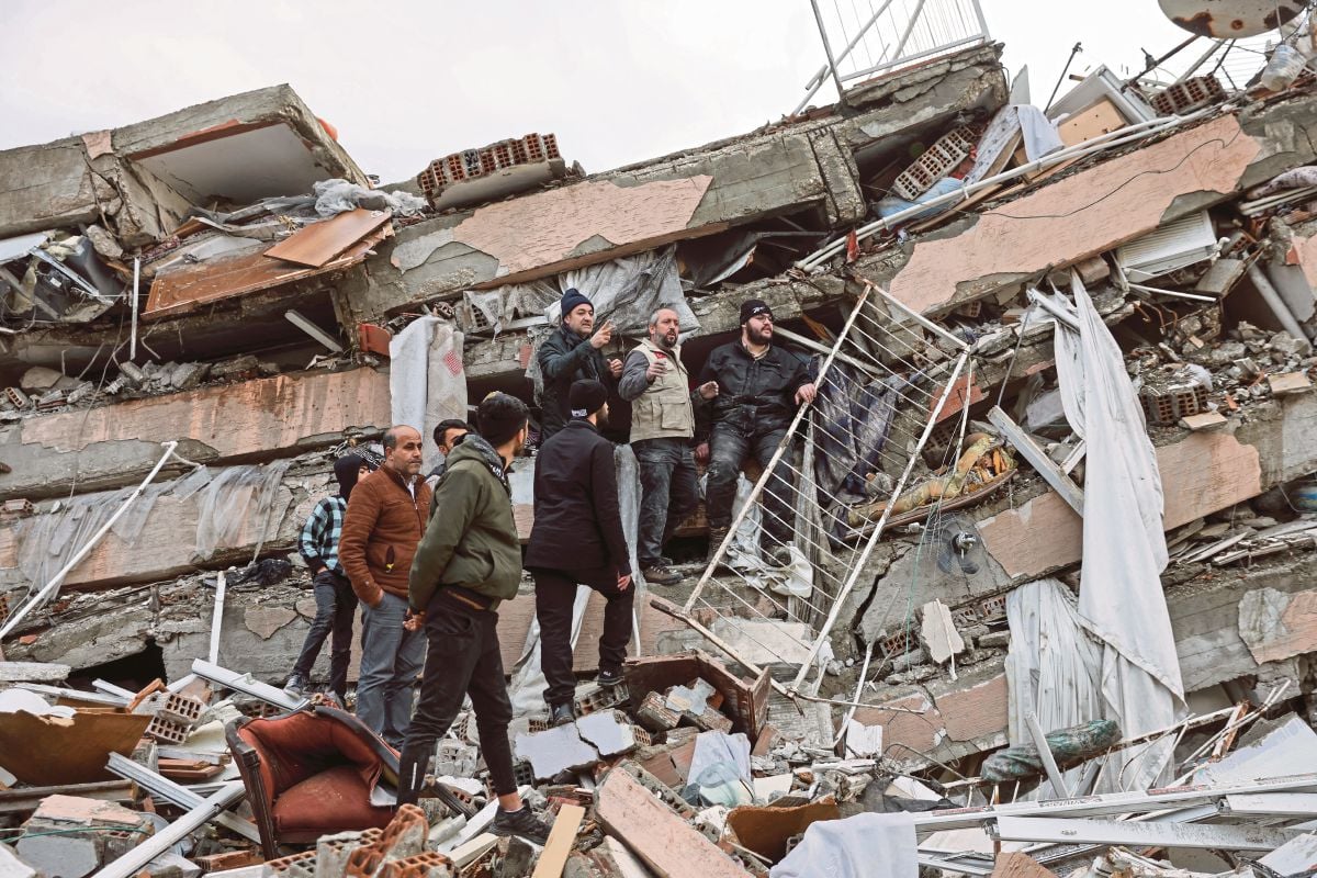 ORANG ramai berjalan di atas bangunan yang runtuh di wilayah Hatay, Turkiye. FOTO Reuters
