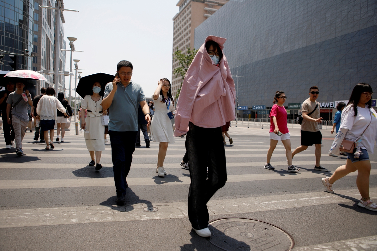 ORANG ramai menggunakan pelbagai cara untuk melindungi diri daripada cuaca panas di Beijing. FOTO Reuters 