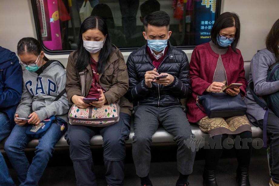 Warga China memakai topeng muka sebagai langkah pencegahan penularan Koronavirus. AFP
