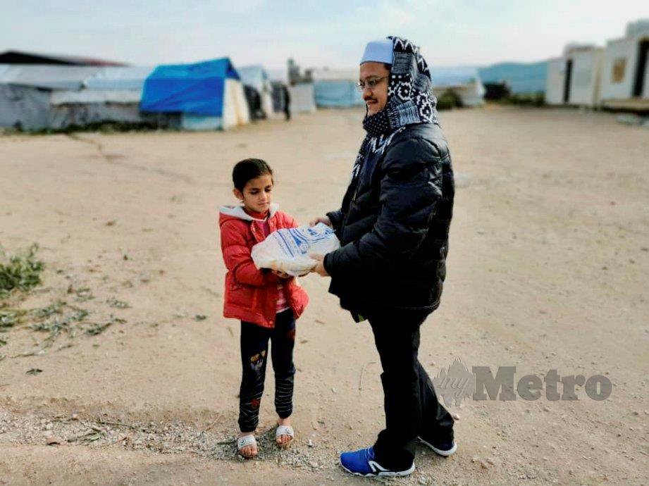 SUKARELAWAN menyerahkan roti kepada kanak-kanak pelarian.