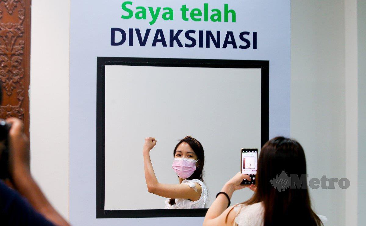 Sukarelawan, Esther Kuok, 27, bergambar kenangan selepas menerima vaksin AstraZeneca di Pusat Dagangan Dunia Kuala Lumpur (WTCKL) pada 16 Mei. FOTO Fariz Iswadi Ismail