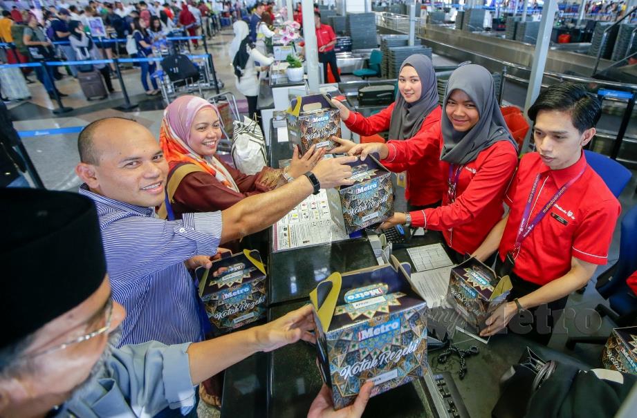 Husin (dua kiri) bersama Norazlinda (tiga kiri) menyerahkan Kotak Rezeki Harian Metro kepada kakitangan syarikat penerbangan di KLIA. FOTO Luqman Hakim Zubir.