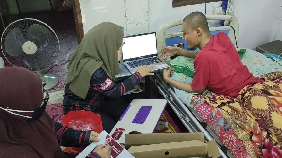 ZURAINI (tengah) menghadiahkan komputer riba kepada Mohamad Hafizi yang terlantar akibat kemalangan jalan raya 20 tahun lalu ketika mengunjungi rumahnya di Kampung Kepala Parit Luar, Tokai. FOTO ZULIATY ZULKIFFLI
