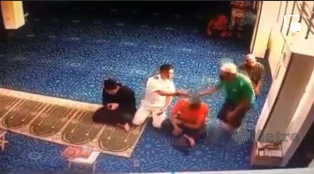 TANGKAP layar rakaman video memaparkan lelaki (baju hijau) menampar kepala jemaah (baju merah) selepas selesai solat di Masjid An-Nur. FOTO tular 
