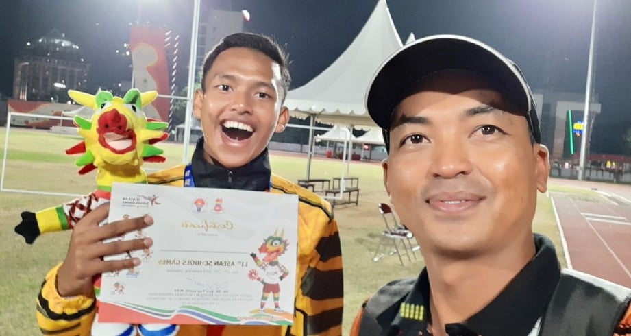HILMI Zakuwan Yusri Azhar (kiri) bersama jurulatihnya, Asro selepas merangkul pingat emas di ‘Asean School Games’ di Indonesia tahun lalu. FOTO Ihsan Sekolah Sukan Malaysia Terengganu