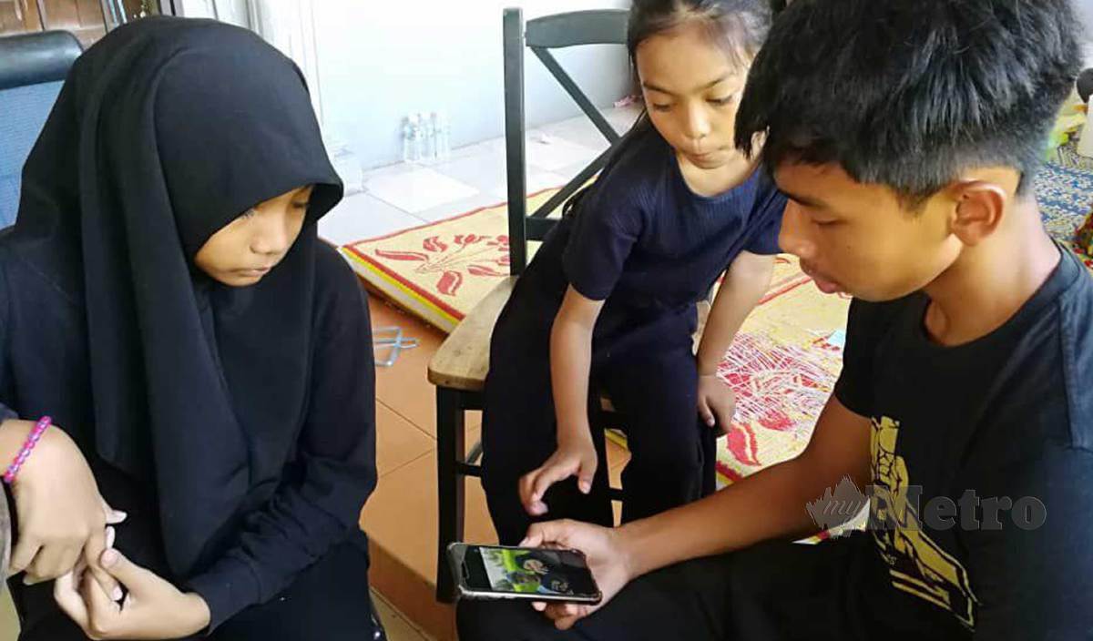 MOHD Amirullah (kanan) bersama dua adiknya, Qistina Amalia dan Qasdina Afiqah melihat gambar ibu dan bapanya. FOTO  Rosli Ilham