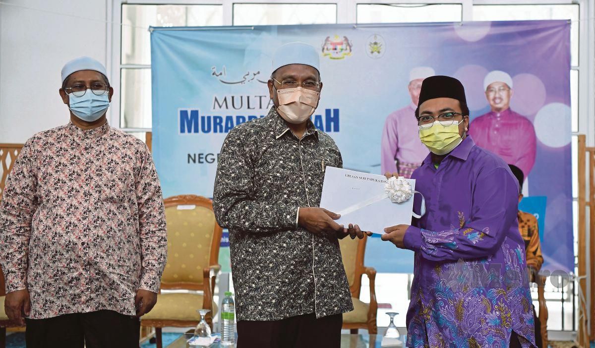  IDRIS (tengah) diiringi Mohd Nor (kiri) menyampaikan surat lantikan guru takmir lantikan 2022 di Masjid Seberang Takir, Kuala Nerus, hari ini. FOTO GHAZALI KORI