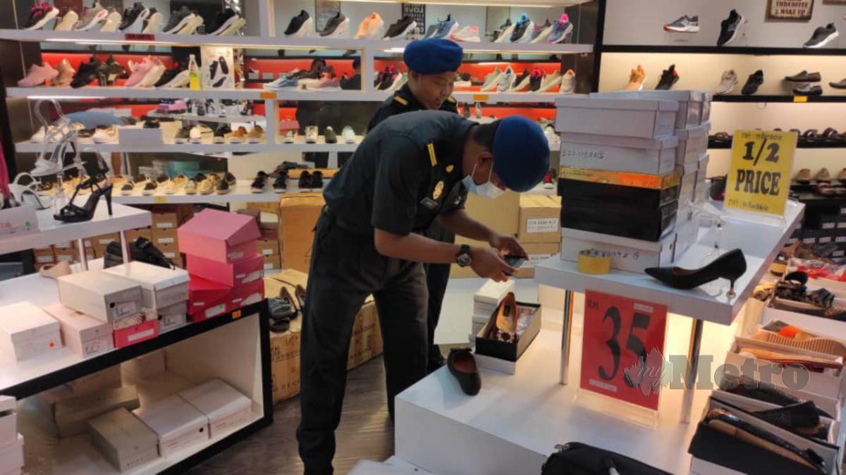 PENGUAT kuasa KPDNHEP memeriksa kasut tiruan yang dijual di premis sebuah pusat beli-belah. FOTO Ihsan KPDNHEP