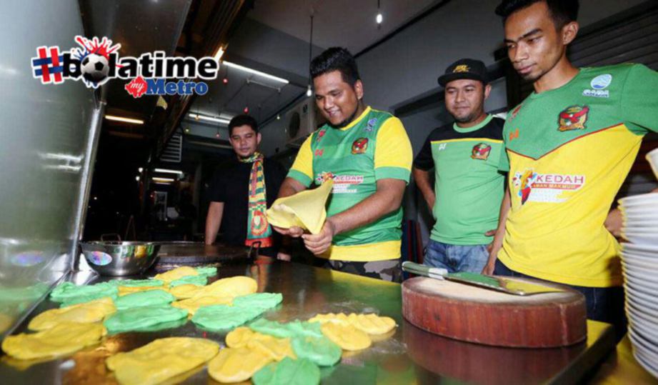 Mohd Najmuddin Mohd Noh (dua dari kiri) menebar roti canai  yang diwarnakan dengan warna hijau kuning di kedai miliknya di Taman Tunku Maheran sempena pasukan bolasepak Kedah mara ke perlawanan akhir Piala Malaysia menentang Selangor pada Ahad ini. FOTO AMRAN HAMID