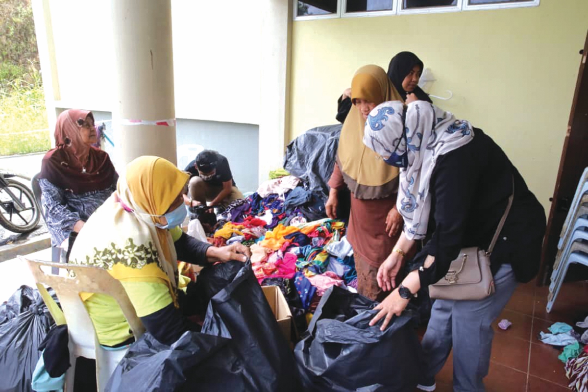 PEMANGKU Ketua Pengarah YaPEIM, Parihah Hasan (kanan) meninjau kumpulan wanita yang sedang memilih pakaian yang di sumbangkan orang ramai di pusat pemindahan sementara, Dewan Serbaguna Kampung Pia, Dong, Raub.
