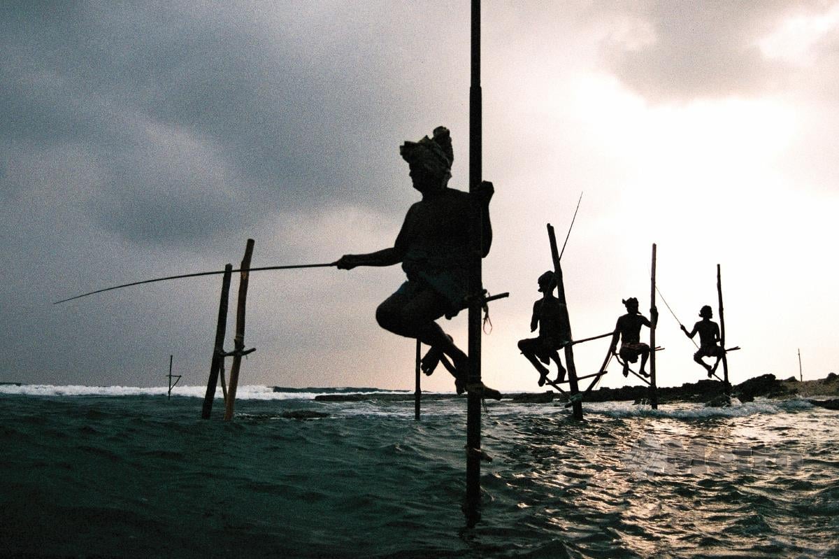 PEMANCING ikan pesisir pantai yang memancing ikan dengan duduk pada sebatang kayu yang dipacak di atas laut berhampiran Pantai Koggala.