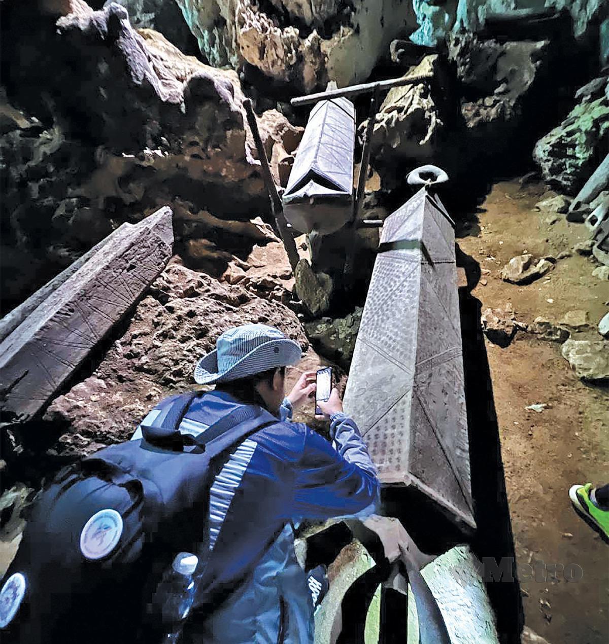 PENGUNJUNG merakam gambar keranda kuno yang masih utuh tersimpan dalam gua.