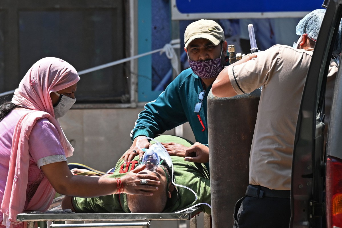 PETUGAS kesihatan membantu pesakit Covid-19 untuk memasuki kereta di sebuah hospital di New Delhi. FOTO AFP 