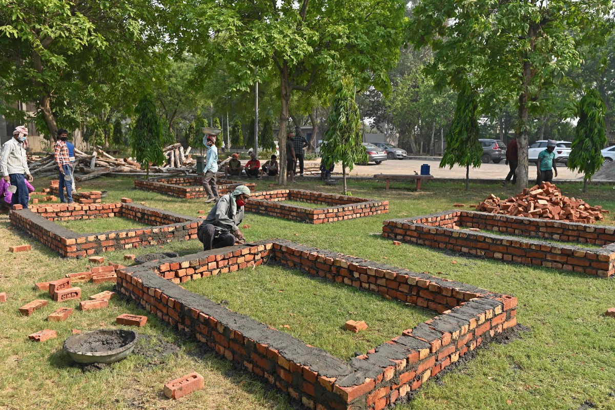 PEKERJA membina tempat sementara untuk pembakaran mayat di sebuah krematorium di New Delhi. FOTO AFP 