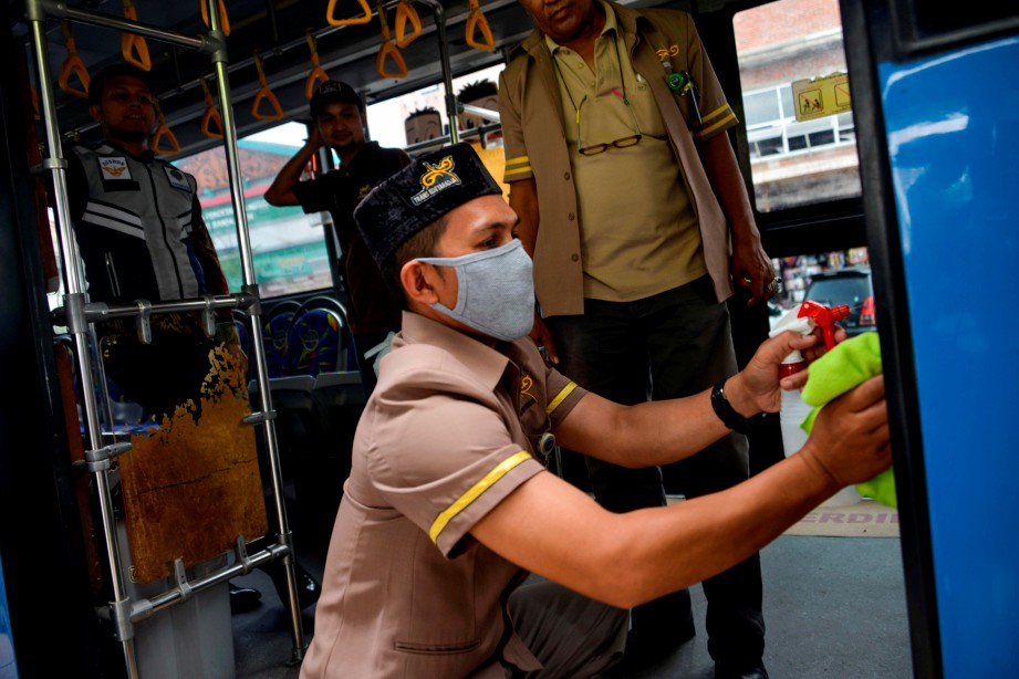 KAKITANGAN menyembur pembasmi kuman di bas di Banda Aceh. FOTO AFP 