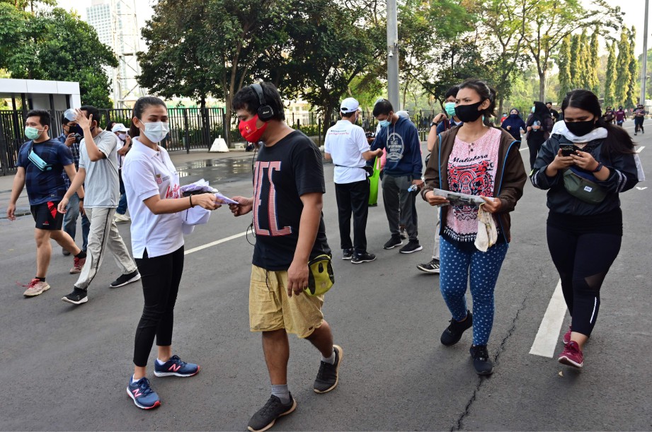 SUKARELAWAN mengedarkan pelitup muka percuma kepada orang ramai di Stadium Gelora Bung Karno, Jakarta. FOTO AFP 