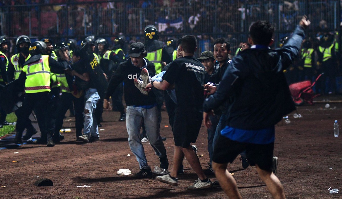 PENYOKONG mengangkat mangsa yang cedera ketika rusuhan di Stadium Kanjuruhan. FOTO AFP