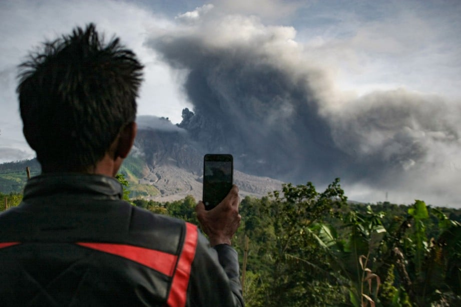 SEORANG lelaki merakam letusan Gunung Berapi Sinabung, di Karo, Sumatera Utara, hari ini. 