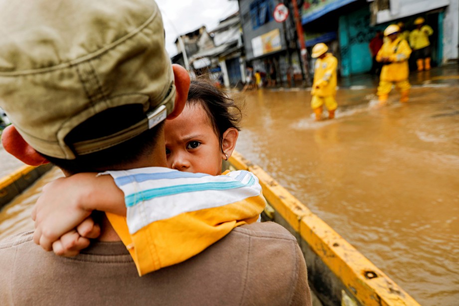 GAMBAR menunjukkan lelaki mendukung anak perempuannya ketika meredah banjir di kawasan Jatinegara, Jakarta. AFOTO Reuters