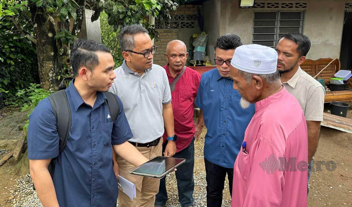 CHE Hussain (kanan) mendengar penerangan daripada wakil MCMC di Kampung Sungai Bayu Dalam. FOTO Paya Linda Yahya
