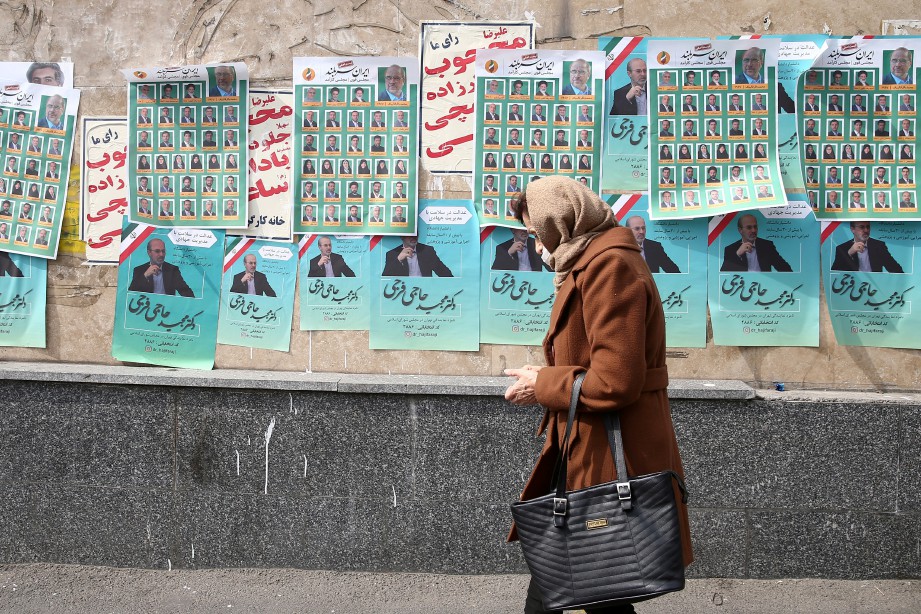 SEORANG wanita melalui kawasan dengan poster pilihan raya Parlimen di Tehran, Iran. FOTO West Asia News Agency/ Reuters