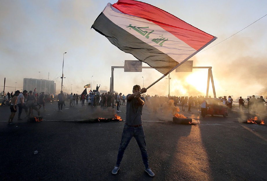 PENUNJUK perasaan anti-kerajaan mengibarkan bendera Iraq ketika pertempuran di Baghdad semalam. FOTO AFP
