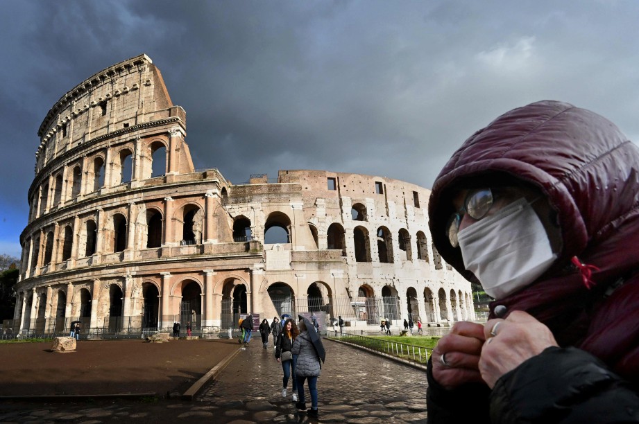 LELAKI memakai penutup mulut dan hidung melalui Coliseum di Rom. FOTO AFP 