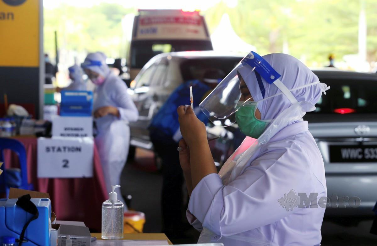 JURURAWAT terlatih sedang menyiapkan picagari yang berisi cecair vaksin sebelum disuntik kepada orang awam yang telah mendapat temujanji bagi suntikan dos kedua di Pusat Pemberian Vaksin (PPV) Pandu Lalu Lapangan Terbang Antarabangsa, Melaka. FOTO Syafeeq Ahmad.