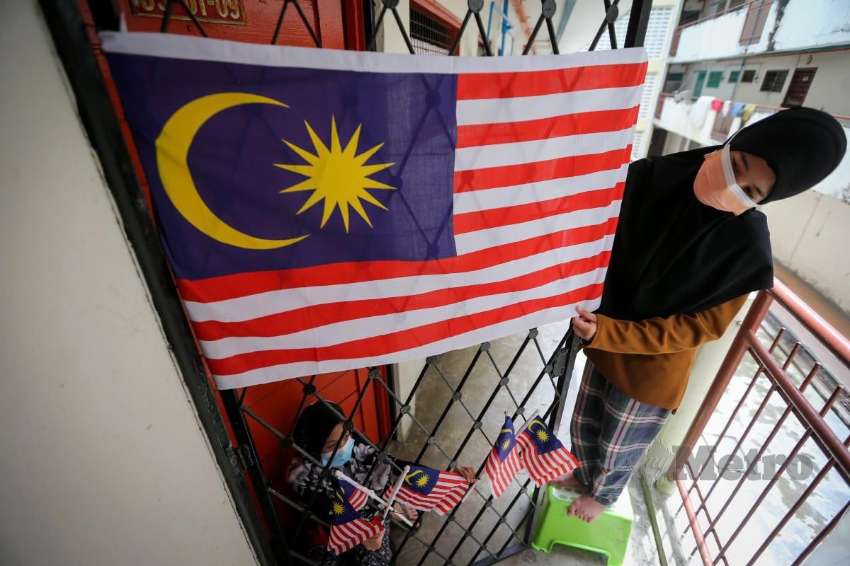 ALYA Soleha (kanan) bersama adiknya Aisyah Zahra menggantung bendera Malaysia di rumahnya. FOTO Aswadi Alias.