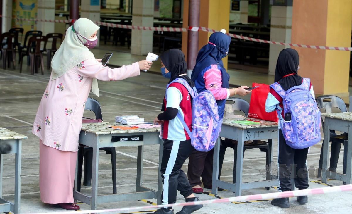 MURID yang hadir diminta mengimbas kod QR dan mengambil bacaan suhu badan sebelum masuk ke kelas di Sekolah Kebangsaan (SK) Angkatan Tentera Johor Bahru, Johor. FOTO Nur Aisyah Mazalan