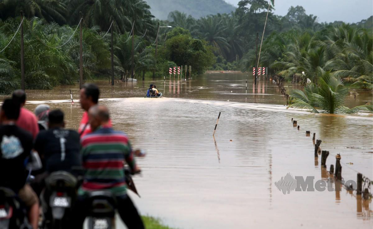 ORANG ramai melihat air banjir  berikutan jalan utama Kuala Krai yang menghubungkan Kampung Kuala Nal dengan Lepan Pauh dan Bukit Sireh terputus. FOTO Nik Abdullah Nik Omar.
